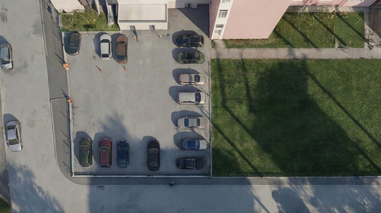 Campus 23 top-down aerial of the parking lot and lawn beside a residential block in low afternoon sun