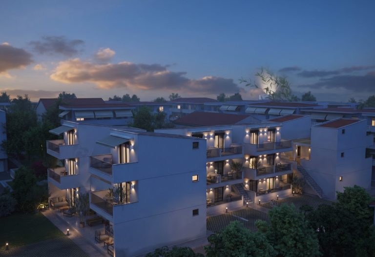 Aerial view of Victoria Residence at dusk, blocks with lit balconies and wall lights under a moonlit sky