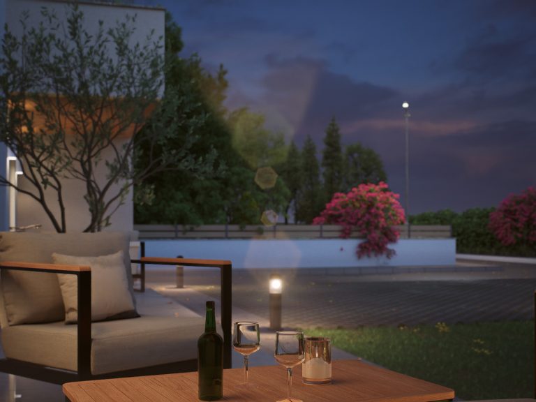 Victoria Residence garden at blue hour, terrace table with wine glasses, lit bollards and flowering shrubs