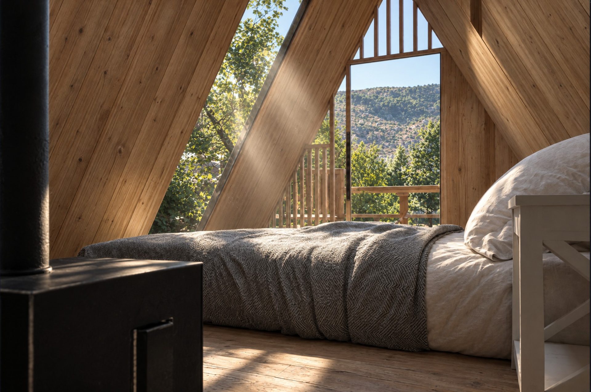 A-frame bedroom with timber walls, sun beam across the bed and the gable open to the hillside